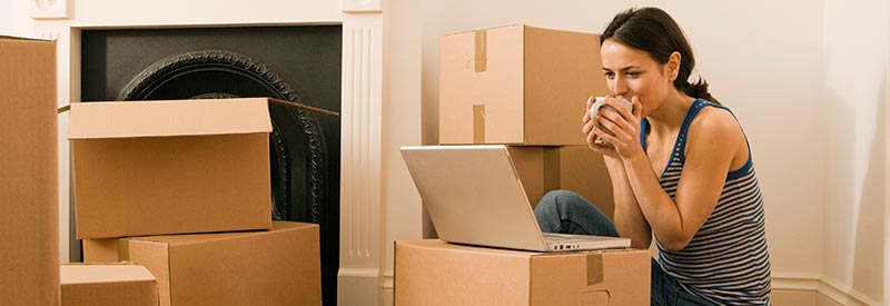 woman drinking coffee while unpacking boxes