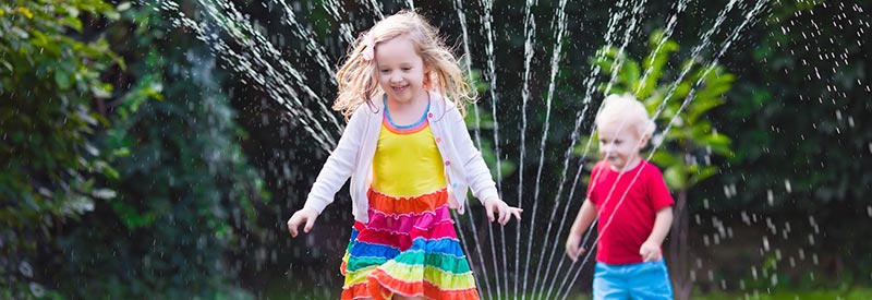 kids running through a lawn sprinkler