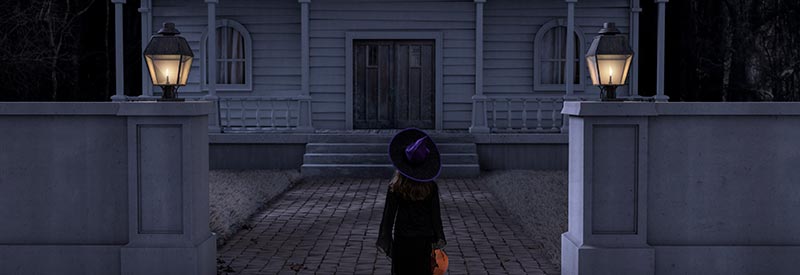 young witch looking at a haunted house